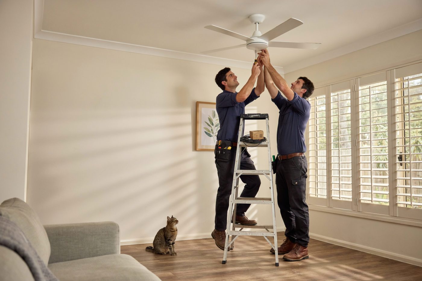 Electrician fitting a ceiling fan in a Queensland living room